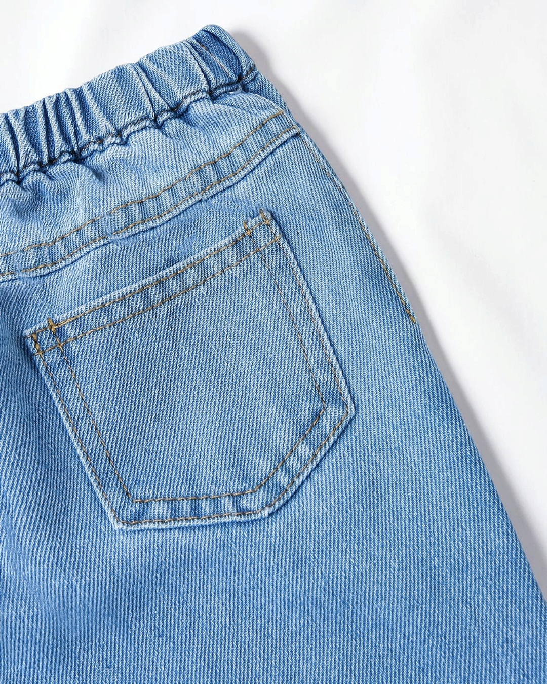 Gros plan sur la poche arrière d'un pantalon en jean bleu Le Cocon d'Or pour petite fille avec taille élastique