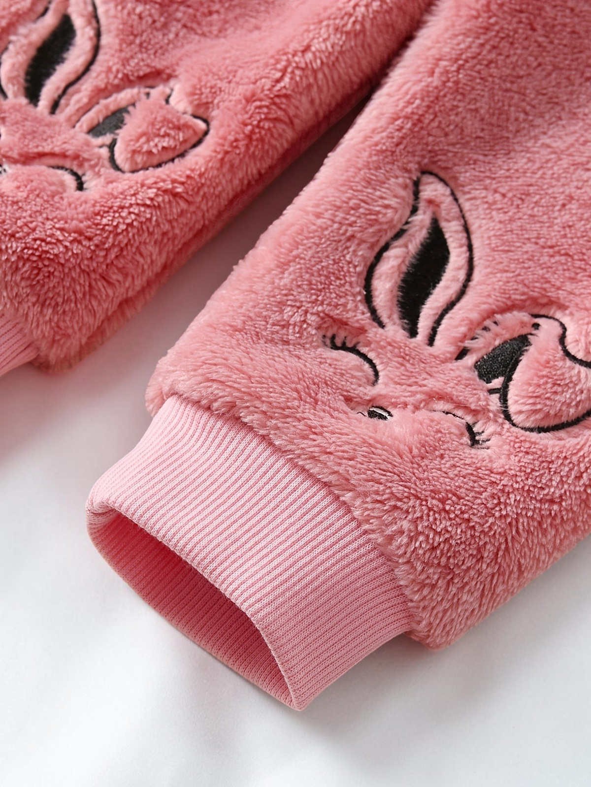 Détail de la manche en peluche rose Le Cocon d'Or avec motif lapin brodé et poignet côtelé pour enfant