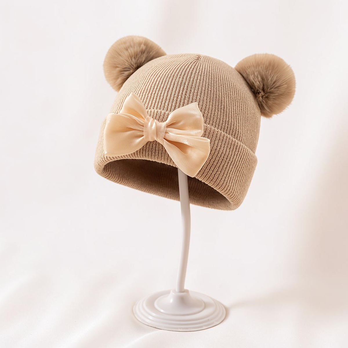 Bonnet bébé beige Le Cocon d'Or en acrylique avec pompons et nœud élégant pour l'automne et l'hiver