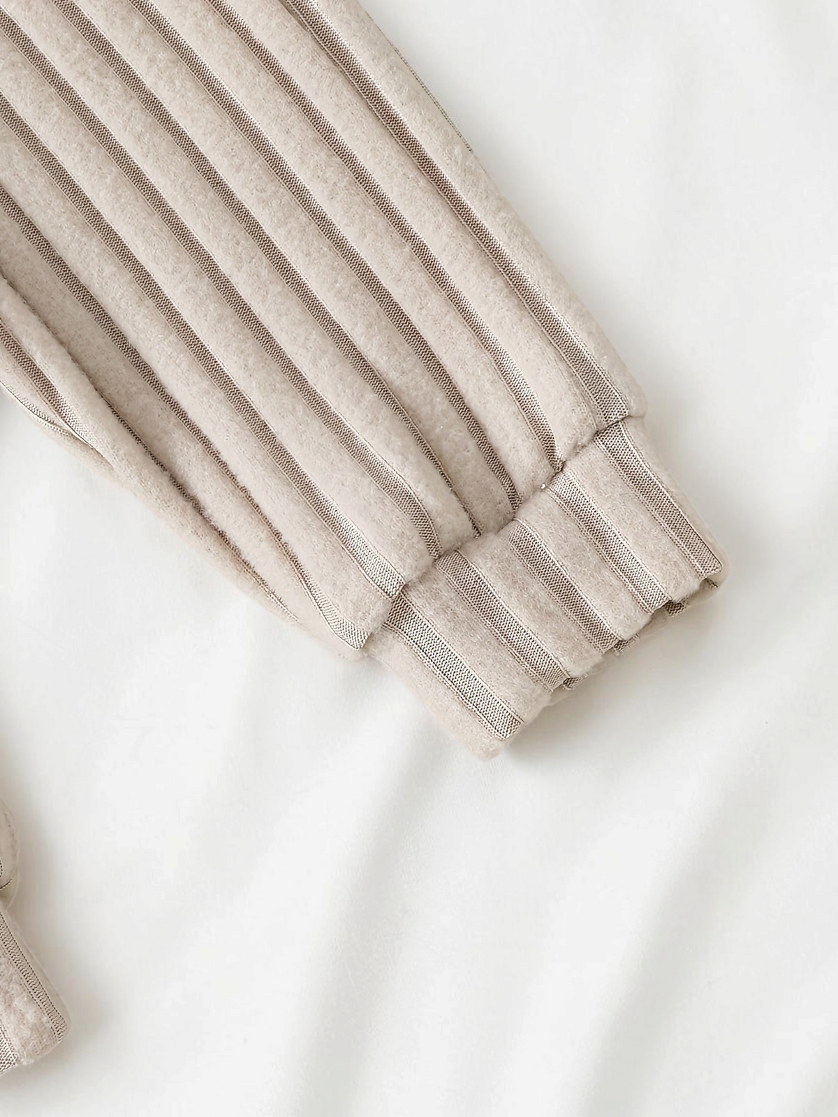 Détail de la manche en maille côtelée beige de l'ensemble bébé garçon Le Cocon d'Or avec poignet élastique