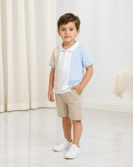 Jeune garçon portant un polo Le Cocon d'Or à demi-zip, design color-block bleu et beige, avec un short assorti