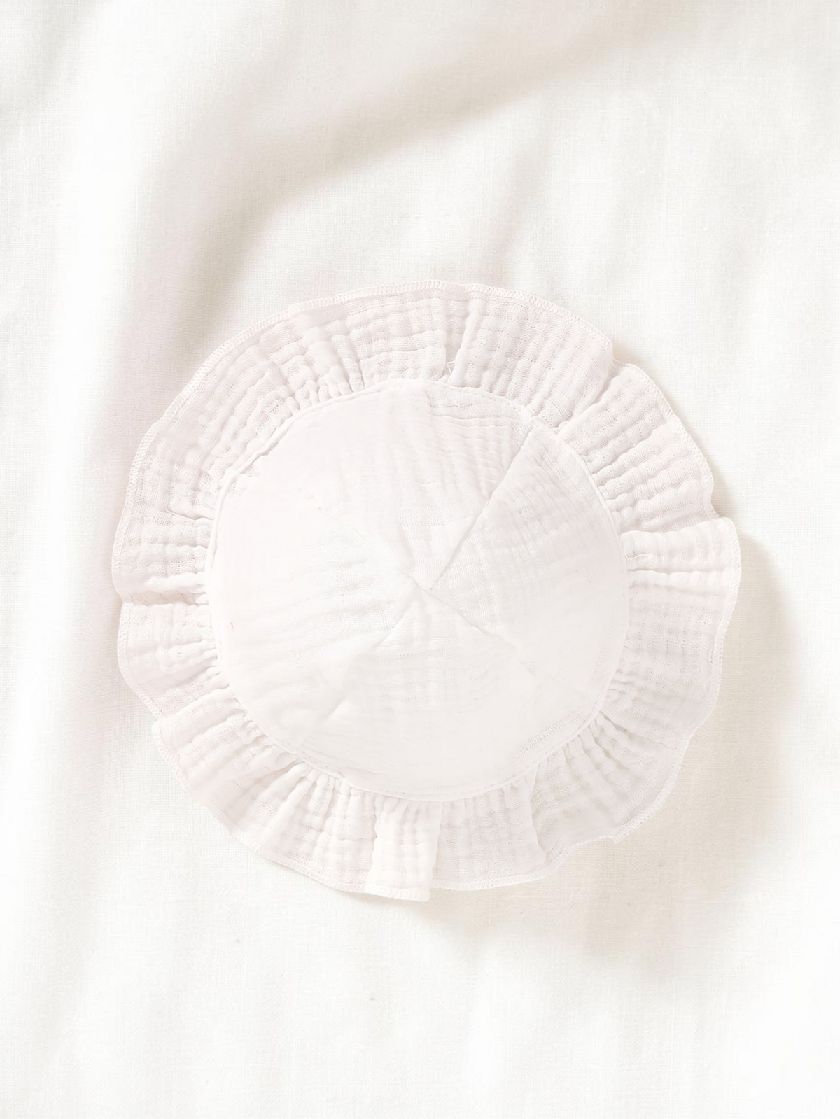 Chapeau de bébé blanc en coton doux avec bordure à volants, accessoire de Le Cocon d'Or pour nouveau-née.