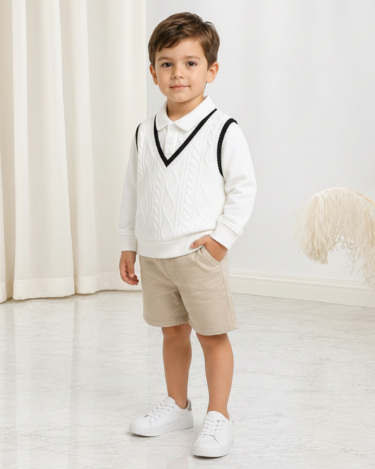 Jeune garçon portant un polo en maille blanc Le Cocon d'Or avec un gilet sans manches assorti et un short beige.