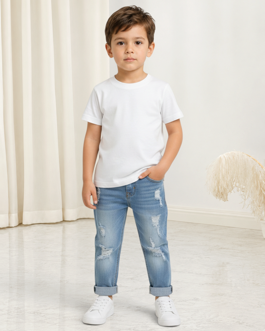 Jeune garçon portant un jean bleu déchiré Le Cocon d'Or avec un t-shirt blanc et des baskets dans un studio lumineux