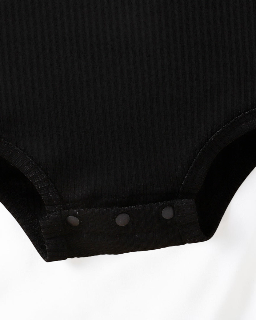 Détail de l'entrejambe à boutons-pression d'un body noir en maille côtelée pour bébé Le Cocon d'Or