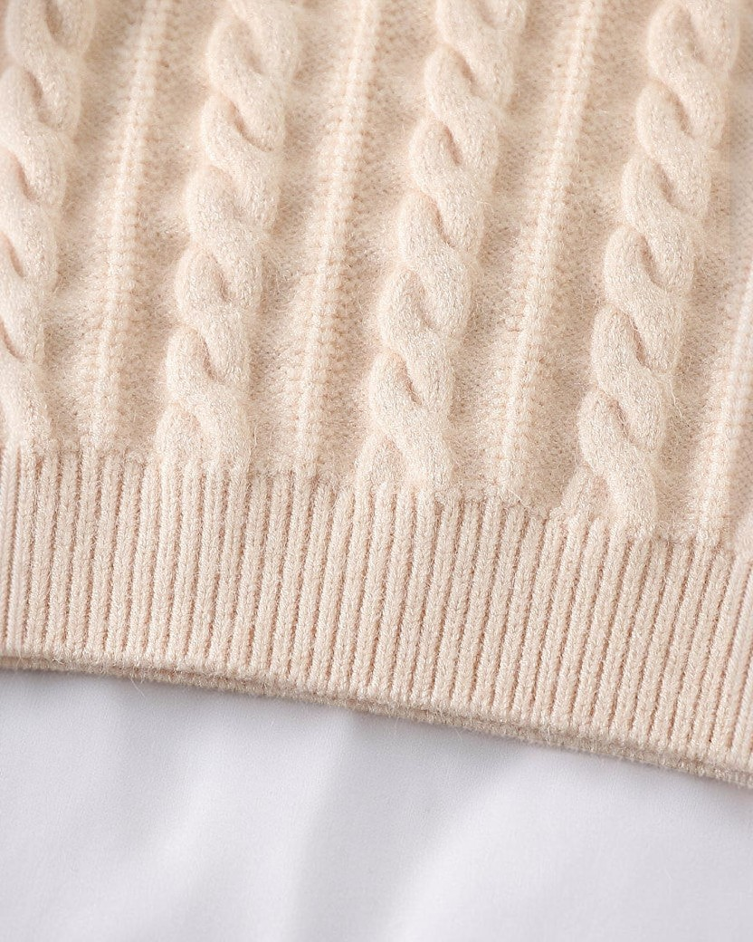 Gros plan sur la maille torsadée beige d'un pull Le Cocon d'Or avec une finition en bord-côte élastique