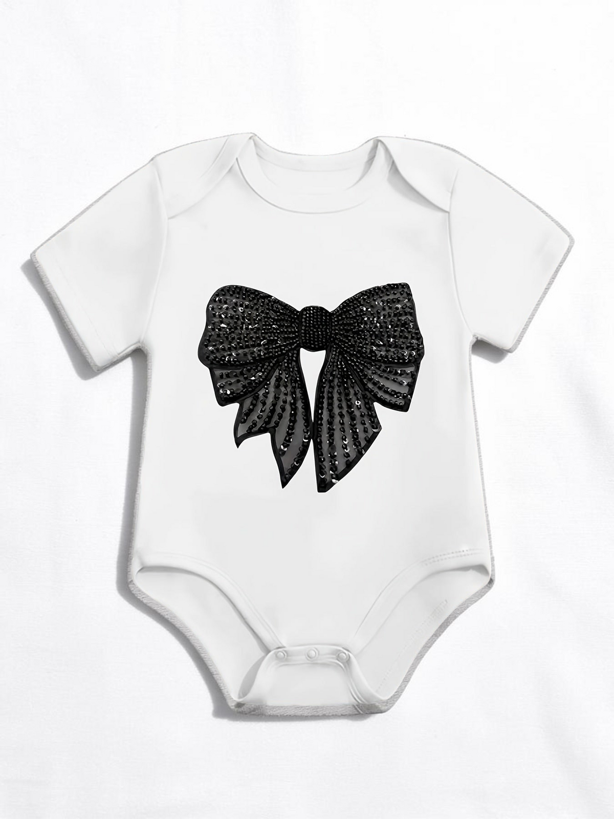 Grenouillère bébé blanche Le Cocon d'Or en coton avec imprimé nœud noir à paillettes et manches courtes
