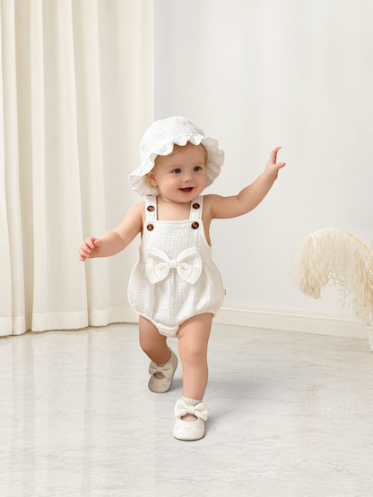 Bébé fille portant un ensemble Le Cocon d'Or blanc en coton avec combinaison à nœud et chapeau assorti