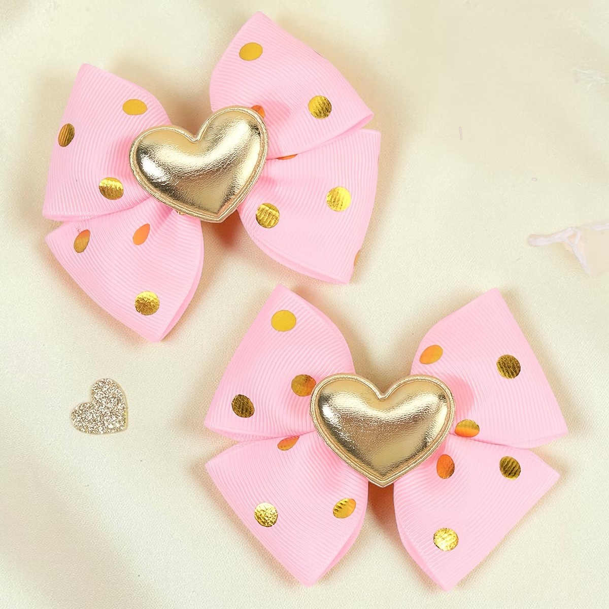 Deux barrettes à cheveux Le Cocon d'Or en tissu rose avec pois dorés et un cœur métallique doré au centre