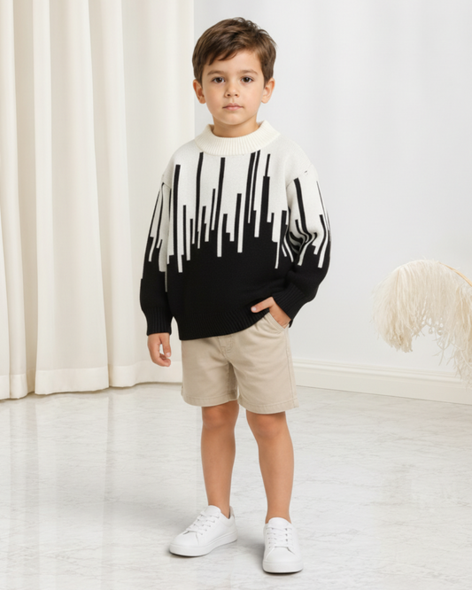 Jeune garçon portant un pull en maille Le Cocon d'Or noir et blanc à motif abstrait avec col rond et manches longues.