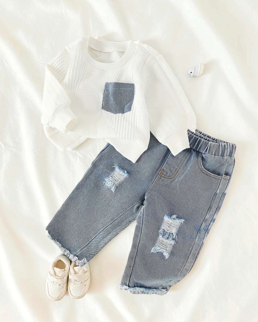 Ensemble Le Cocon d'Or pour petite fille avec haut blanc texturé et jean bleu déchiré à ourlet brut