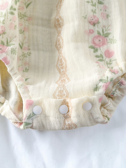 Détail de l'entrejambe à boutons-pression d'un body Le Cocon d'Or en tissu tissé blanc à motif floral rose