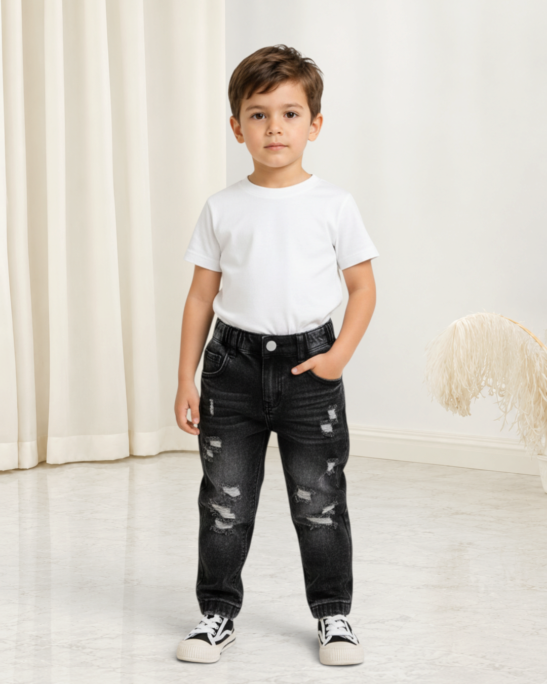 Jeune garçon portant un pantalon Le Cocon d'Or noir dégradé style denim usé avec une ceinture élastique confortable