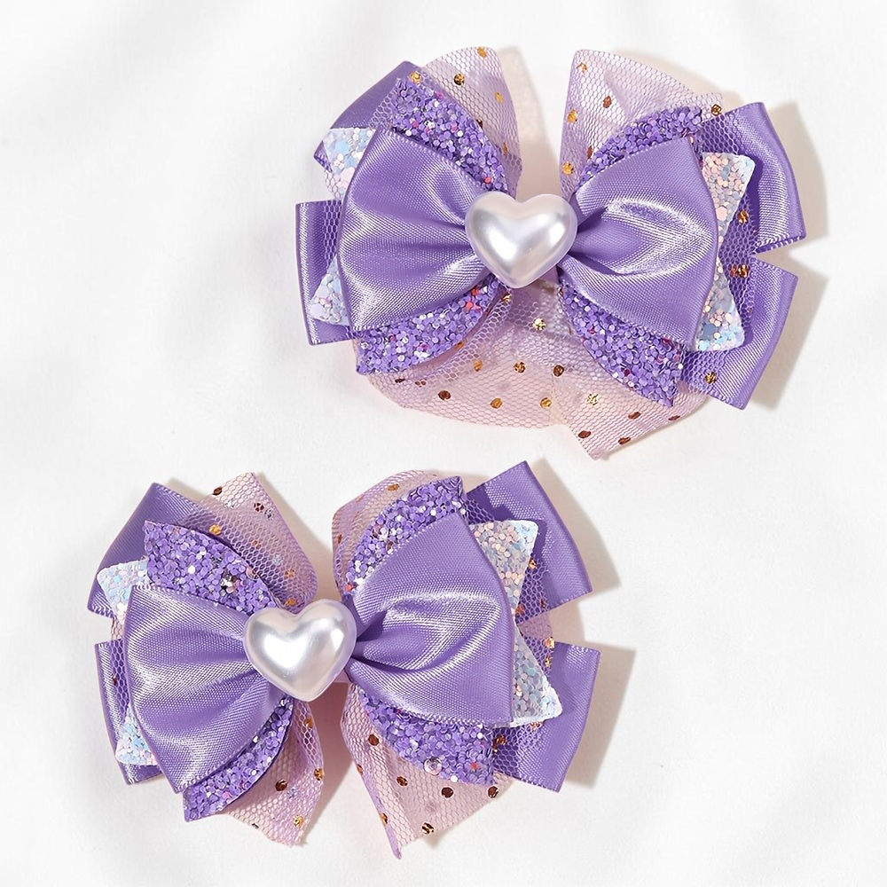 Deux barrettes à cheveux Le Cocon d'Or violettes avec nœuds en satin, tulle pailleté et cœur central nacré
