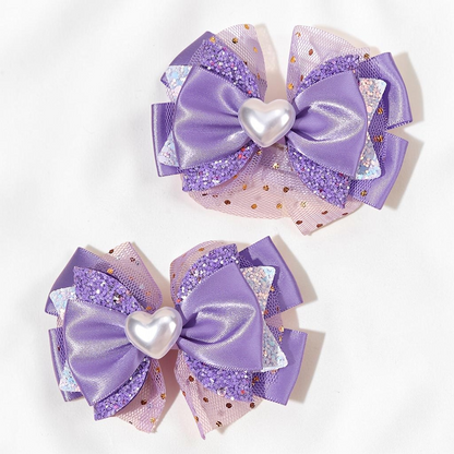 Deux barrettes à cheveux Le Cocon d'Or violettes avec nœuds en satin, tulle pailleté et cœur central nacré