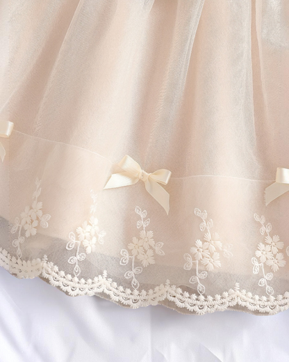 Détail de la robe de baptême Le Cocon d'Or en maille beige avec broderies florales délicates et petit nœud