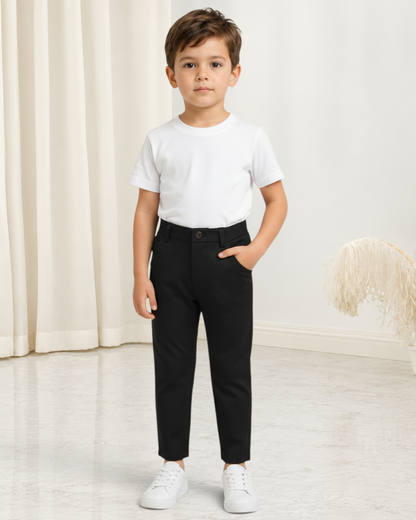 Jeune garçon portant un pantalon de costume noir Le Cocon d'Or avec un t-shirt blanc et des baskets