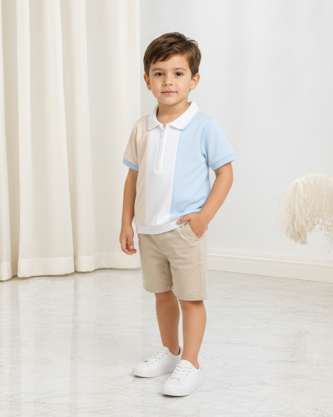 Jeune garçon portant un polo Le Cocon d'Or à demi-zip, design color-block bleu et beige, avec un short assorti