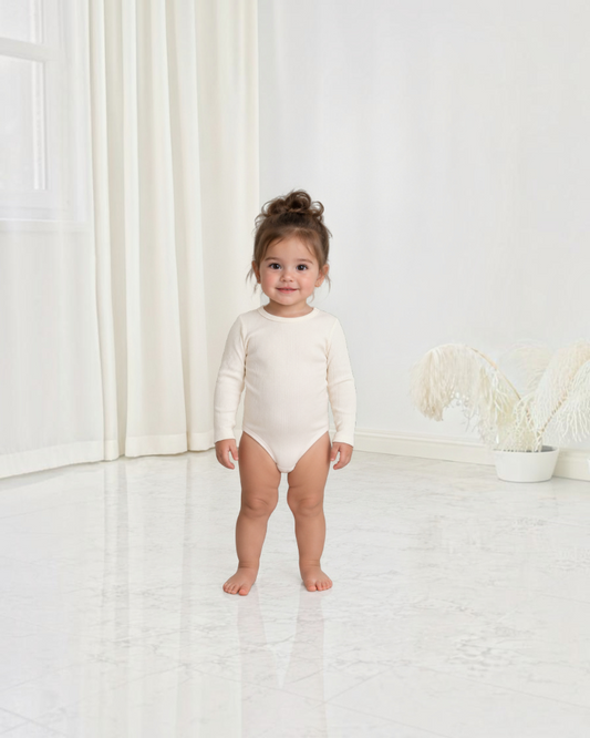 Bébé portant un body Le Cocon d'Or en coton côtelé beige à manches longues, style mignon et confortable
