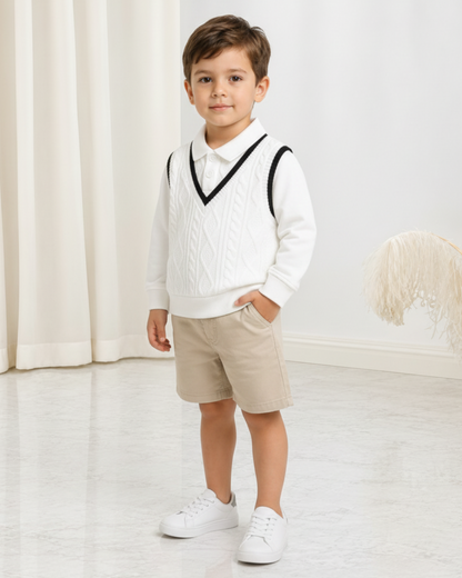 Jeune garçon portant un polo en maille blanc Le Cocon d'Or avec un gilet sans manches assorti et un short beige.