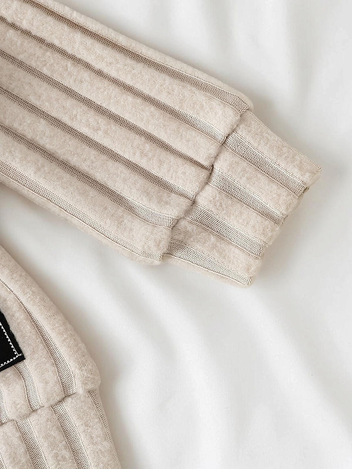 Gros plan sur la manche en maille côtelée beige de l'ensemble bébé garçon Le Cocon d'Or en polyester doux