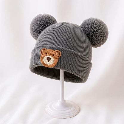 Bonnet bébé gris Le Cocon d'Or en acrylique avec pompons et motif ours brodé pour l'hiver