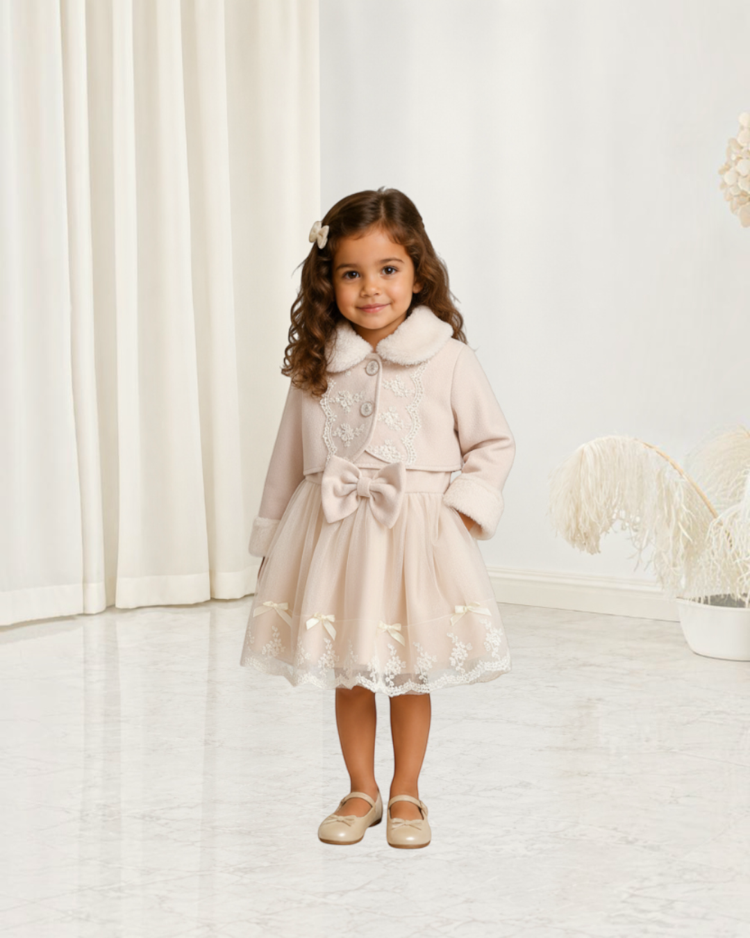 Petite fille portant un ensemble Le Cocon d'Or beige avec robe en maille, nœud papillon et manteau en fausse fourrure