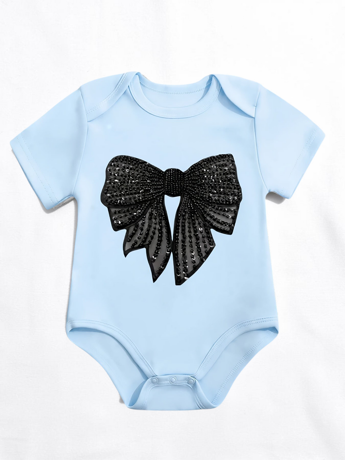 Grenouillère bébé Le Cocon d'Or bleu ciel en coton avec un grand nœud noir à paillettes imprimé sur le devant