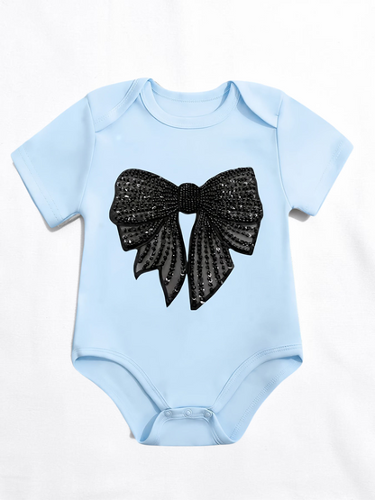 Grenouillère bébé Le Cocon d'Or bleu ciel en coton avec un grand nœud noir à paillettes imprimé sur le devant