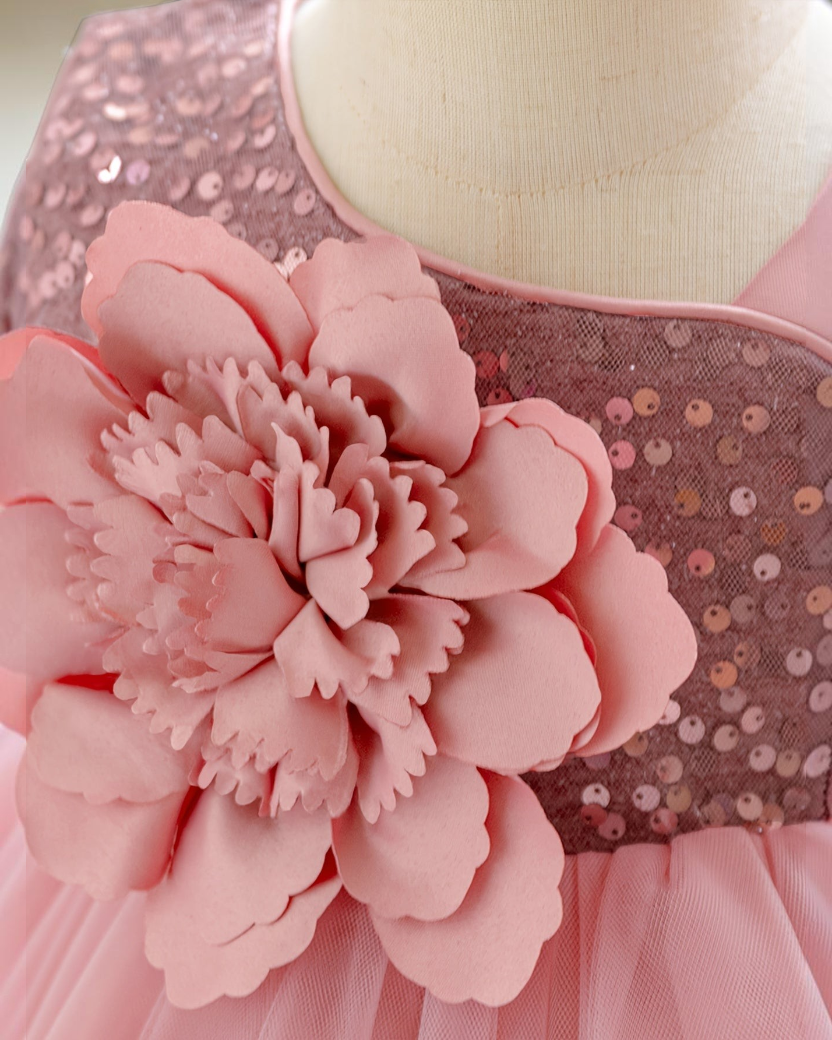 Gros plan sur une robe de princesse Le Cocon d'Or rose avec des sequins scintillants et une grande fleur en relief