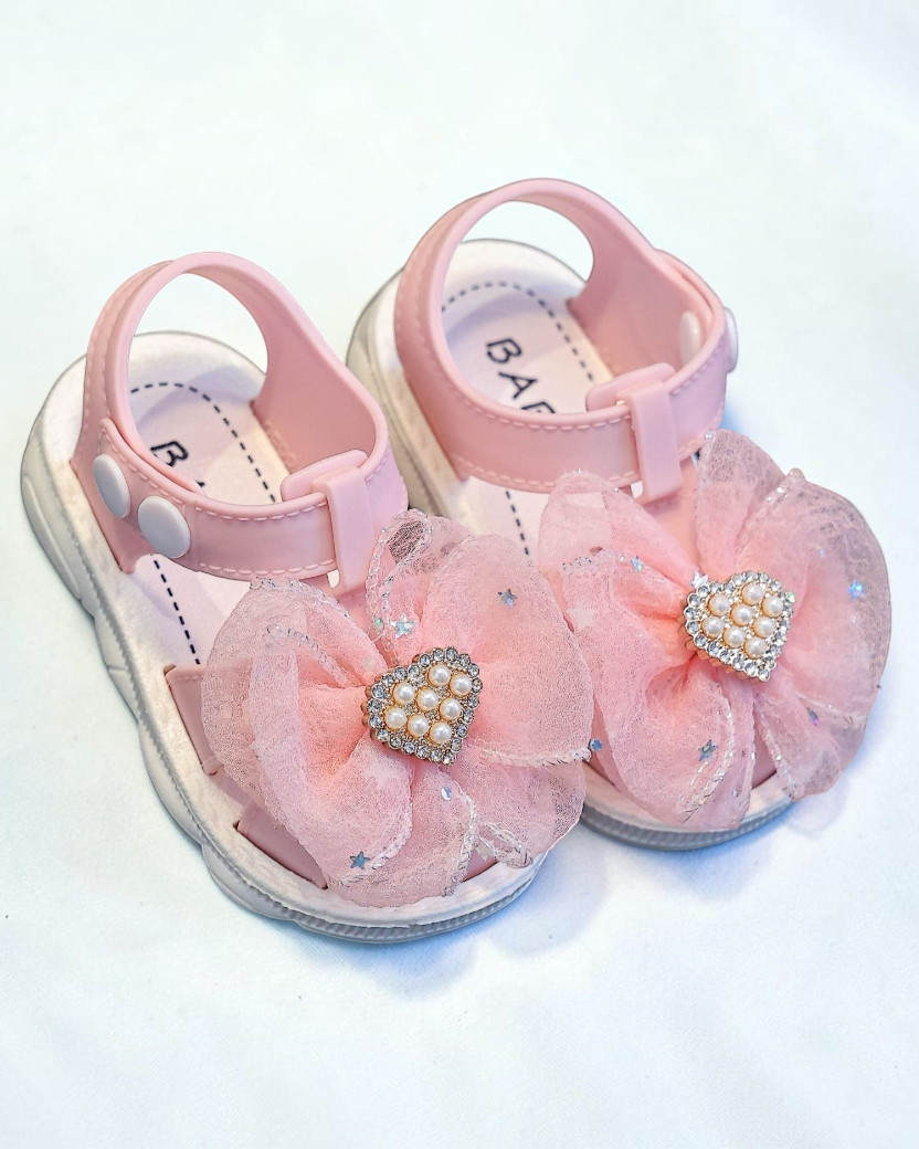 Sandales Le Cocon d'Or pour filles en PVC rose avec nœud en tulle, perles et cœur en strass, fermeture à boucle.