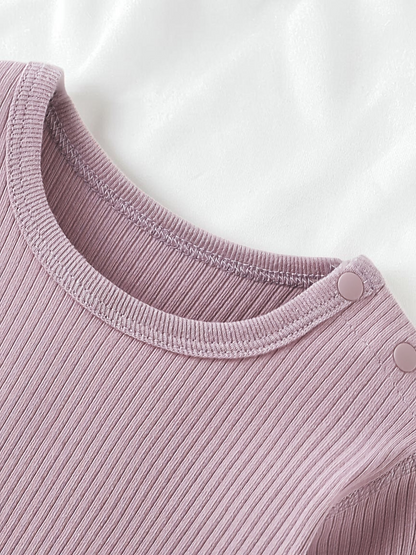Détail du col rond et boutons pression d'un body Le Cocon d'Or en coton côtelé mauve pour bébé