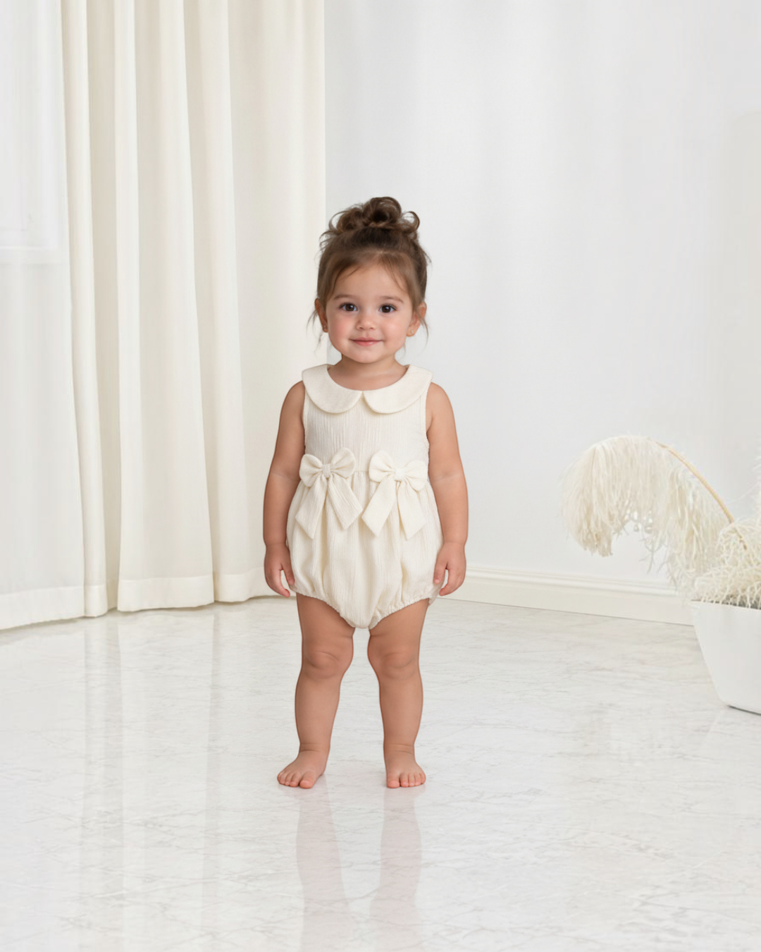 Petite fille portant une combinaison Le Cocon d'Or beige en polyester avec col claudine et nœuds décoratifs