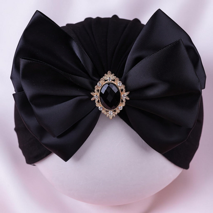 Turban noir Le Cocon d'Or pour bébé avec un grand nœud en satin et une broche centrale ornée de strass