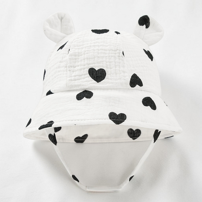 Chapeau bob blanc Le Cocon d'Or en coton respirant pour bébé avec motif cœurs noirs et petites oreilles d'ours