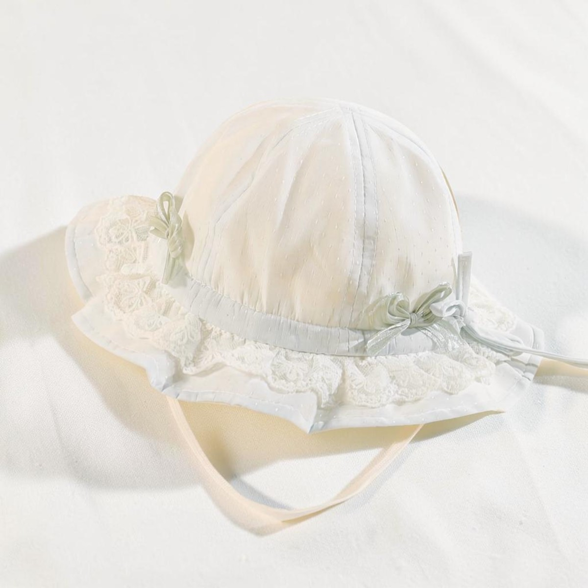 Chapeau de pêcheur blanc Le Cocon d'Or pour bébé en dentelle respirante avec nœuds décoratifs et mentonnière