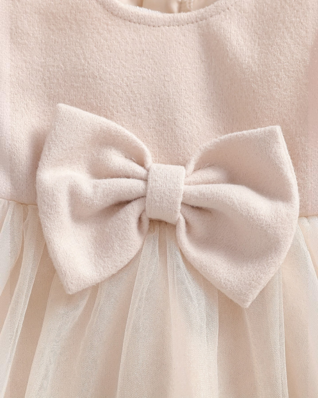 Gros plan sur le nœud papillon décoratif d'une robe Le Cocon d'Or en maille beige pour petite fille