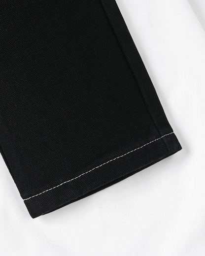 Gros plan sur le bas de jambe d'un jean noir Le Cocon d'Or pour bébé garçon avec surpiqûres blanches contrastantes