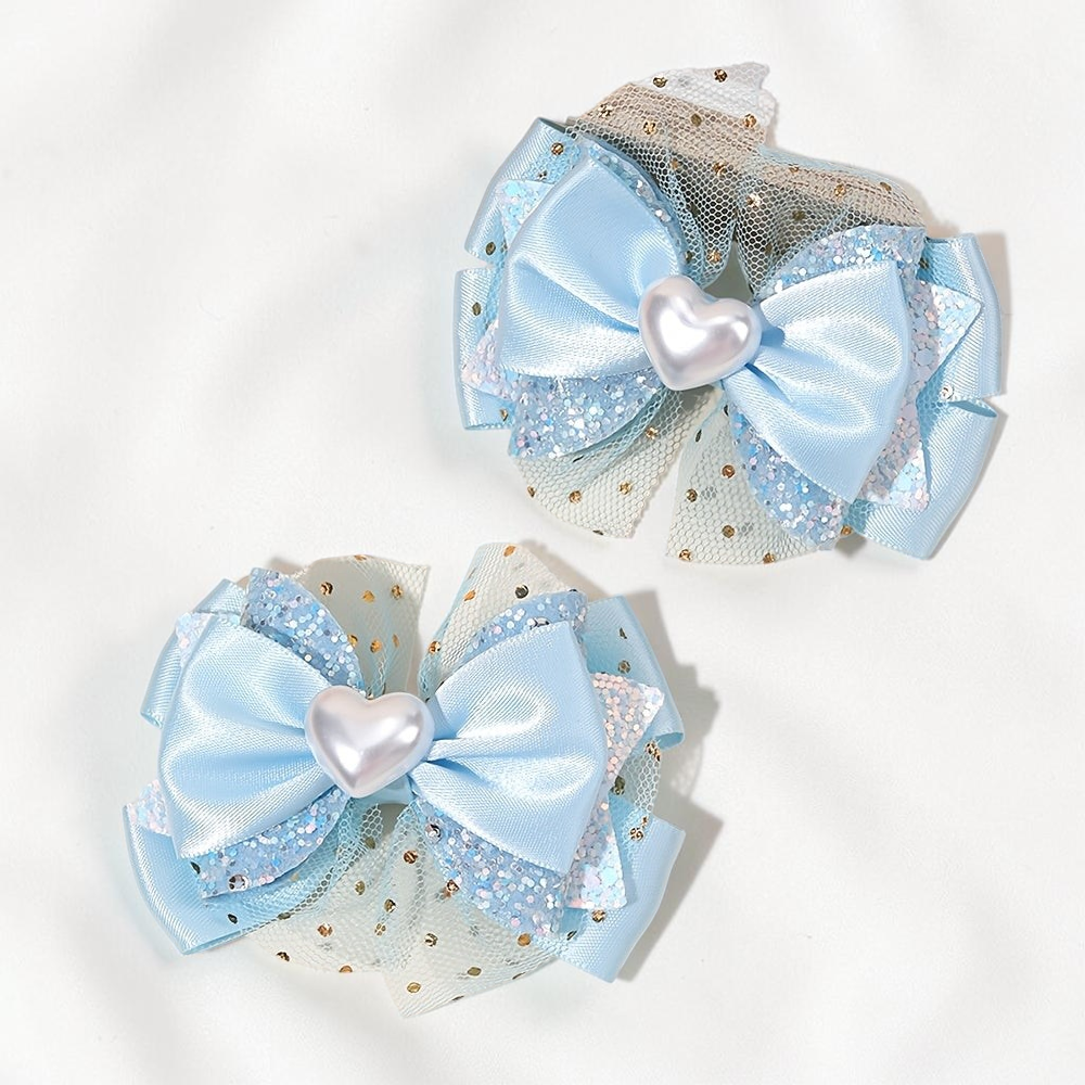 Paire de barrettes Le Cocon d'Or bleu clair en forme de nœud avec tulle pailleté et cœur central nacré