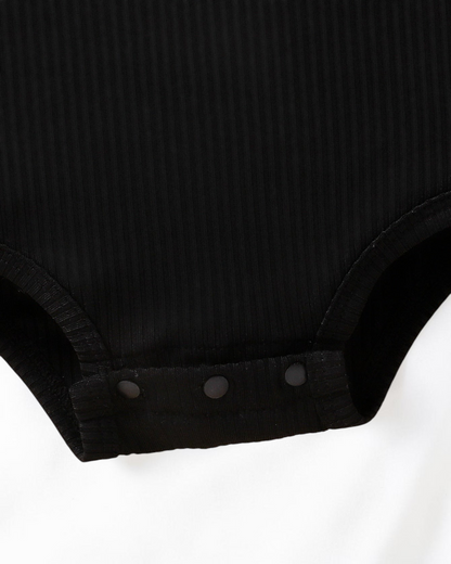 Détail de l'entrejambe à boutons-pression d'un body noir en maille côtelée pour bébé Le Cocon d'Or