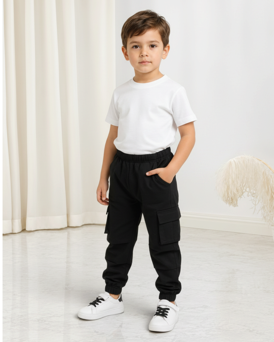 Garçon portant un pantalon cargo noir Le Cocon d'Or en coton avec poches latérales et chevilles élastiques
