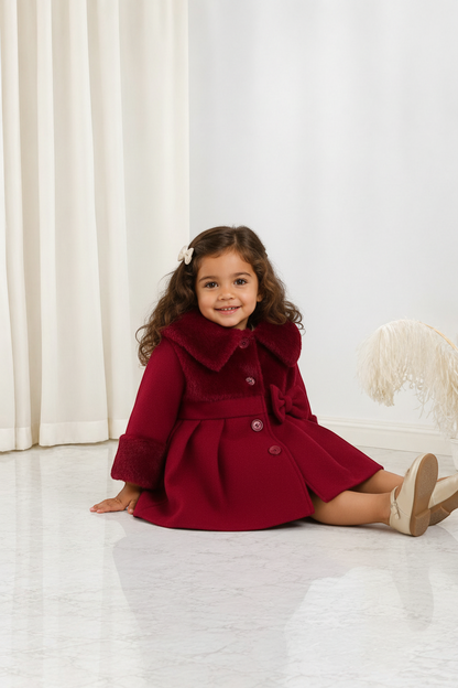 Petite fille portant un manteau d'hiver rouge Le Cocon d'Or avec col à revers, détails en fourrure et nœud