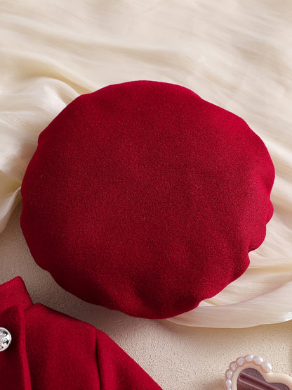 Béret rouge élégant pour bébé fille de la collection Le Cocon d'Or posé sur un tissu crème délicat
