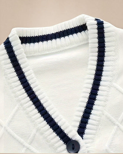 Gros plan sur le cardigan Prestige Knit de Le Cocon d'Or, blanc avec col en V, bordures contrastées bleu marine et boutons.