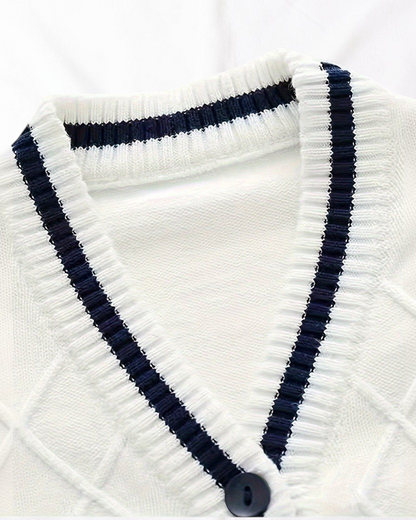 Gros plan sur le cardigan Prestige Knit de Le Cocon d'Or, blanc avec col en V, bordures contrastées bleu marine et boutons.