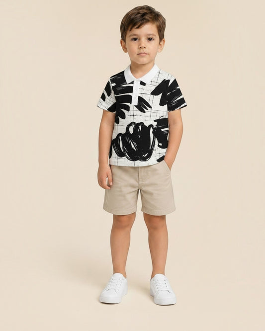 Jeune garçon portant un polo Le Cocon d'Or à motif abstrait noir et blanc avec col classique et short beige