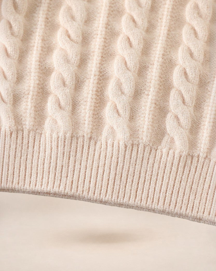 Gros plan sur la maille torsadée beige d'un pull Le Cocon d'Or avec une finition en bord-côte élastique