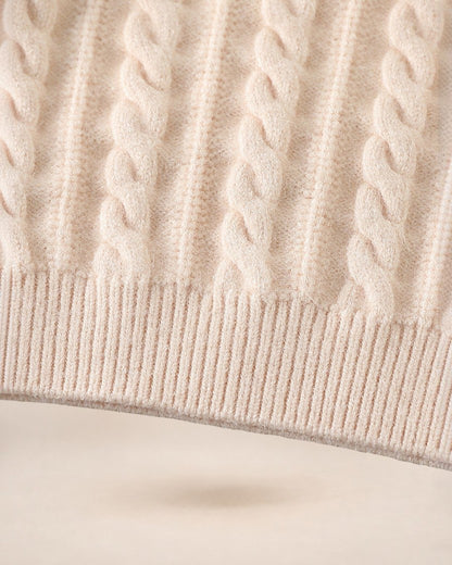 Gros plan sur la maille torsadée beige d'un pull Le Cocon d'Or avec une finition en bord-côte élastique