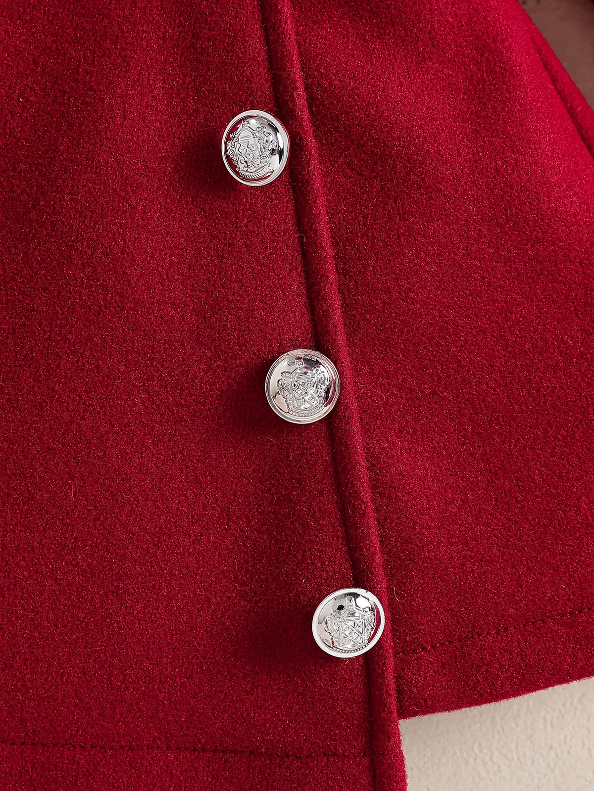 Gros plan sur les boutons décoratifs argentés de la robe rouge Le Cocon d'Or pour bébé fille