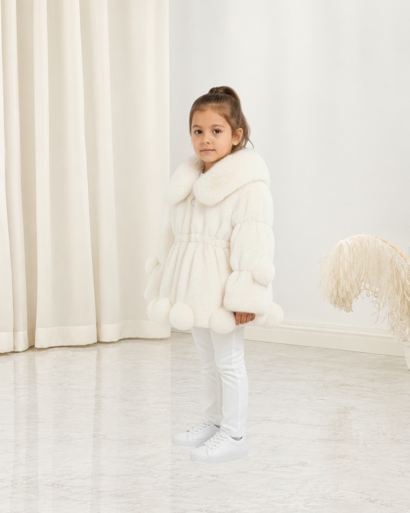 Jeune fille portant une veste en polaire blanche Le Cocon d'Or avec col à revers et détails à pompons
